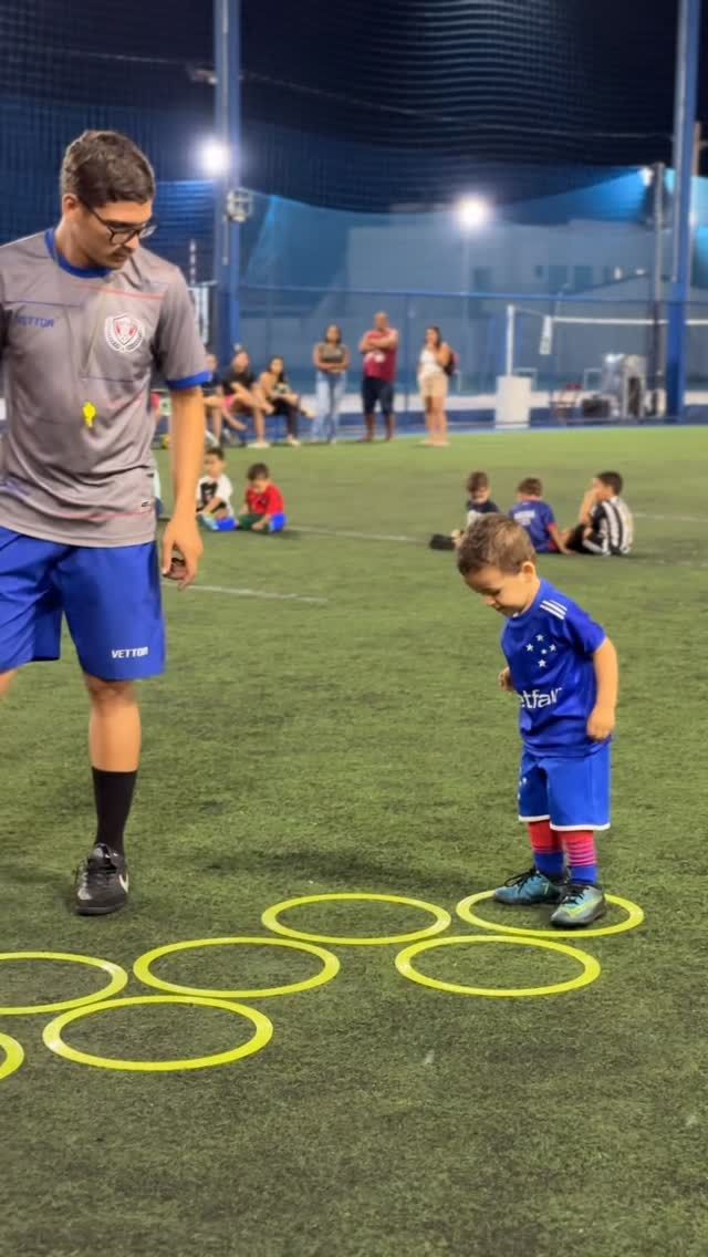 Professor conduzindo criança no circuito de argolas do baby fut