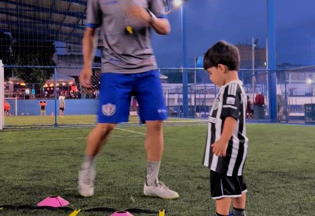 Professor orientando criança no treino de baby fut