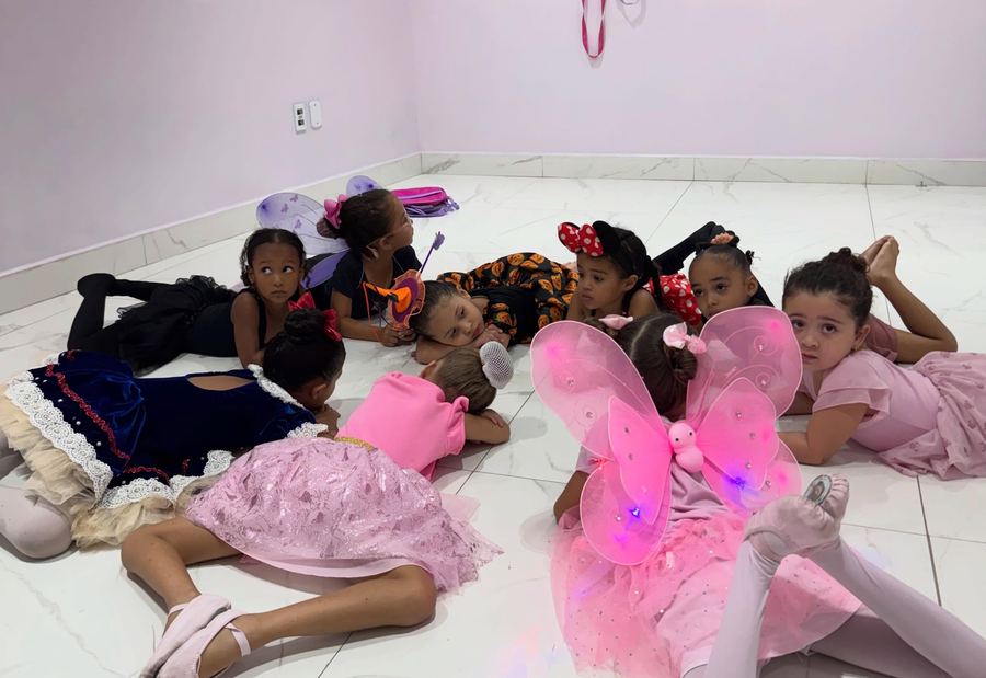 Professora de ballet orientando o alongamento das alunas