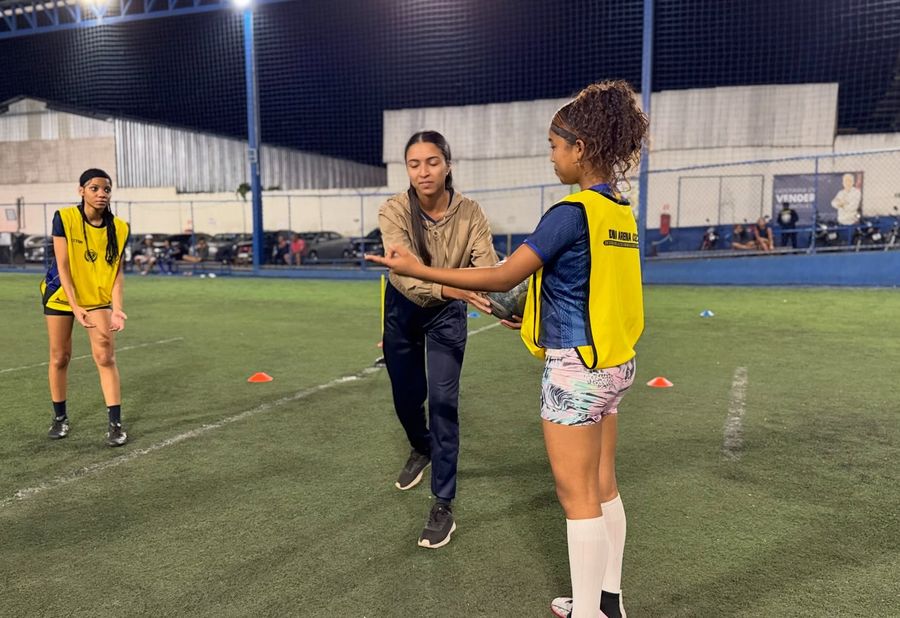 Professora orientando aluna no fundamento com a bola