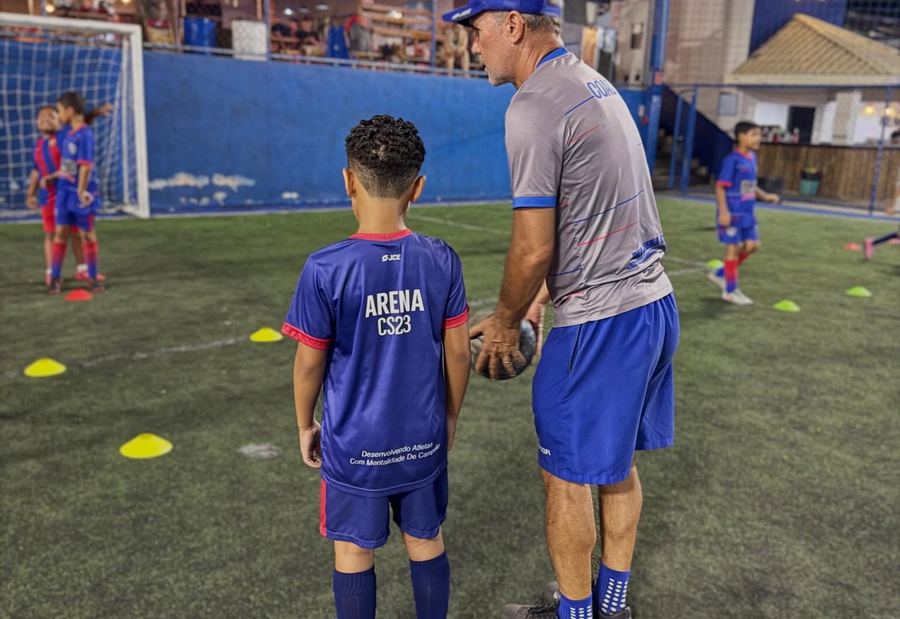 Professor orientando aluno da escola de futebol society