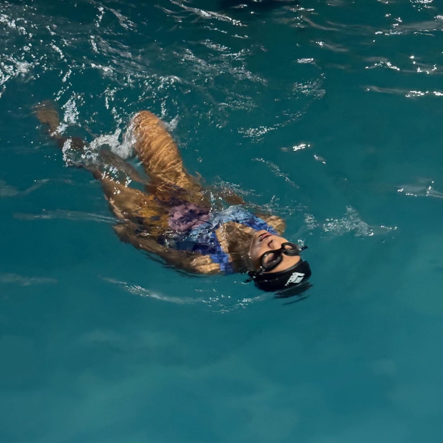Aluna nadando de costas na piscina da Arena CS23